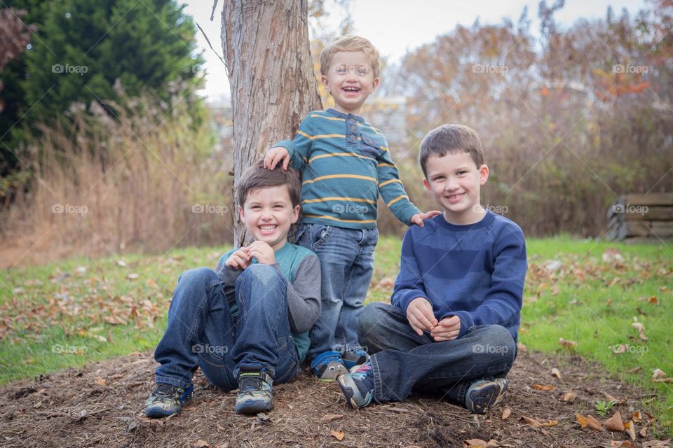 Portrait of happy three boys under the tree