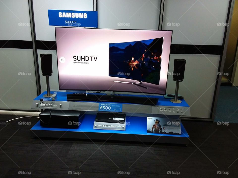 Samsung SUHD curved television displayed with soundbar and sub-woofer blu-ray player and wireless 360 speakers