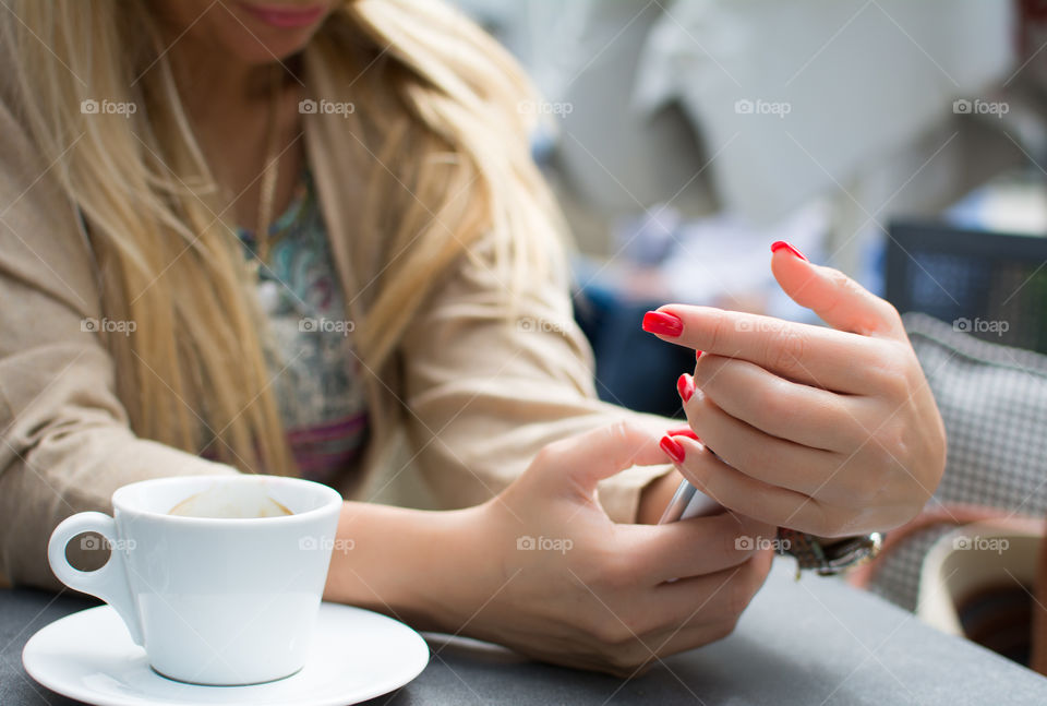 Woman sitting in café holding mobile phone