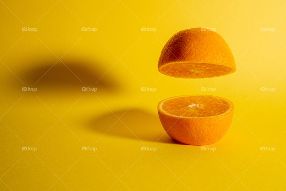 Fresh orange fruit sliced in half with one half floating