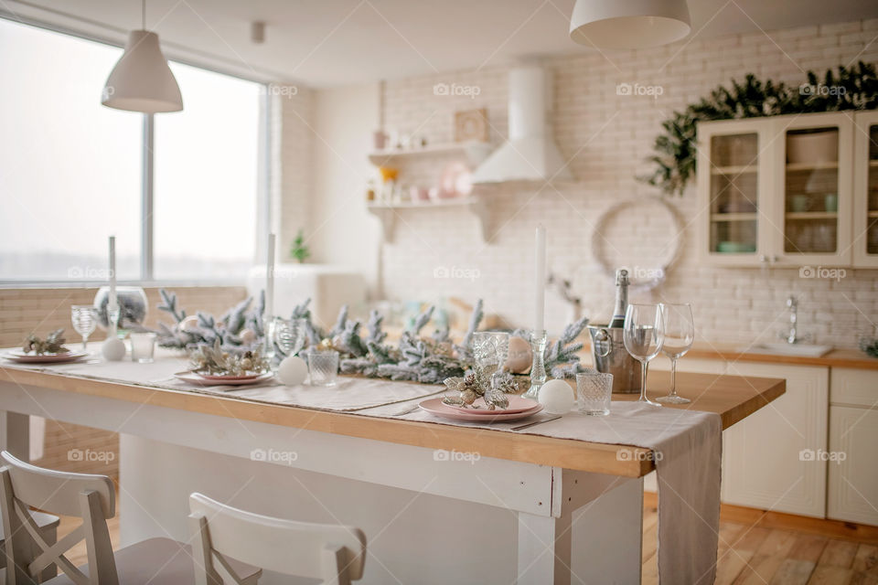 Festive winter cozy kitchen interior with garlands, decorations and gifts.  Christmas dinner at the decorated table.