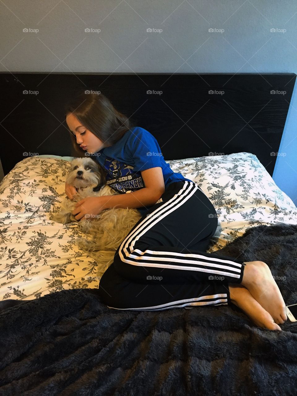 Girl her dog with lying on bed