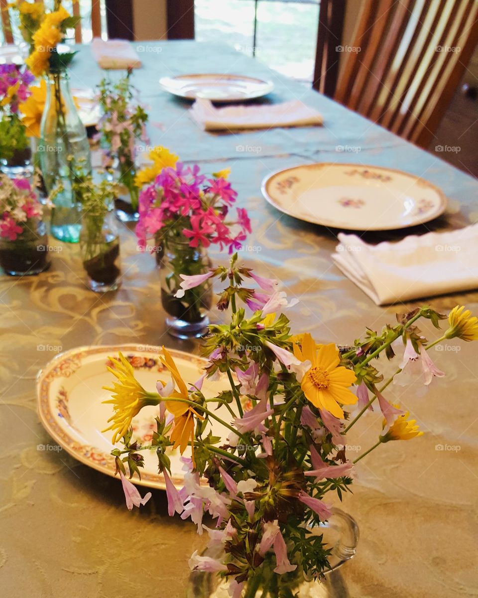 Fresh wildflowers in glass containers decorate a spring dining room table