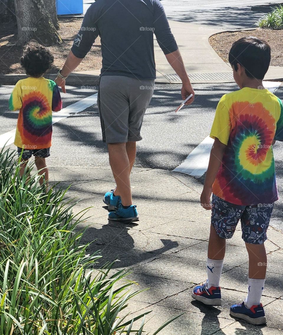 father walking with two sons wearing matching rainbow color t-shirts at an Oregon library in Summer