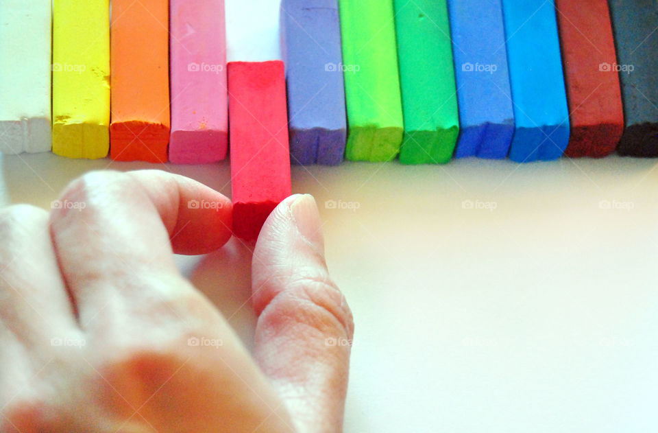 Making decisions, which chalk color, top view, hands holding red chalk