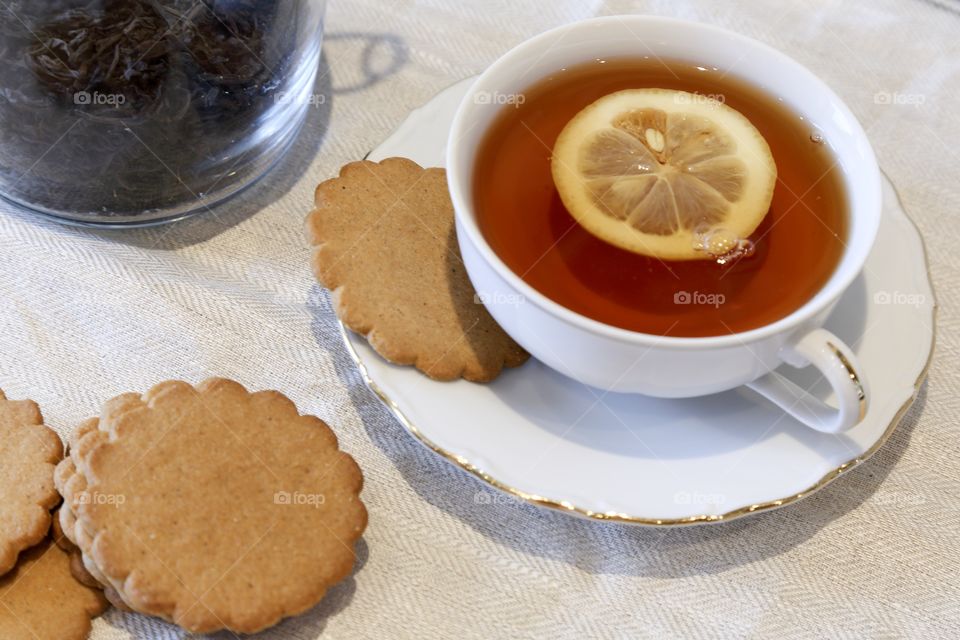 Close-up of lemon tea in cup and biscuit