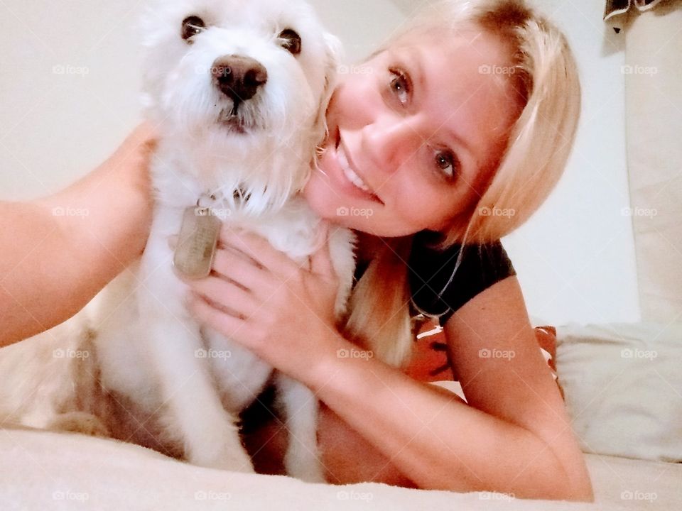 young woman posing for a picture with her small white dog