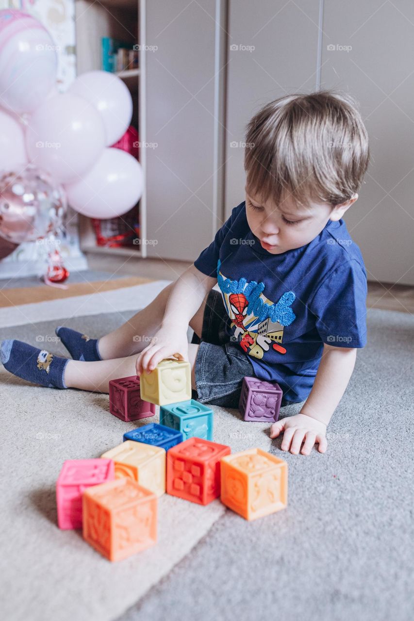 little boy playing with colorful cubes