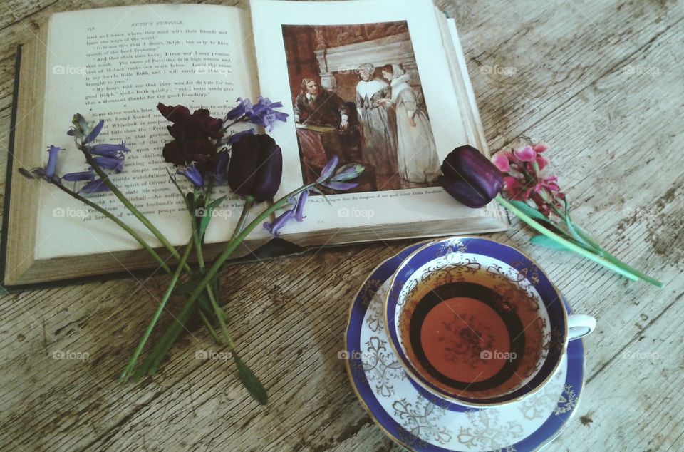 An old children's book,  A cup of tea and spring flowers.