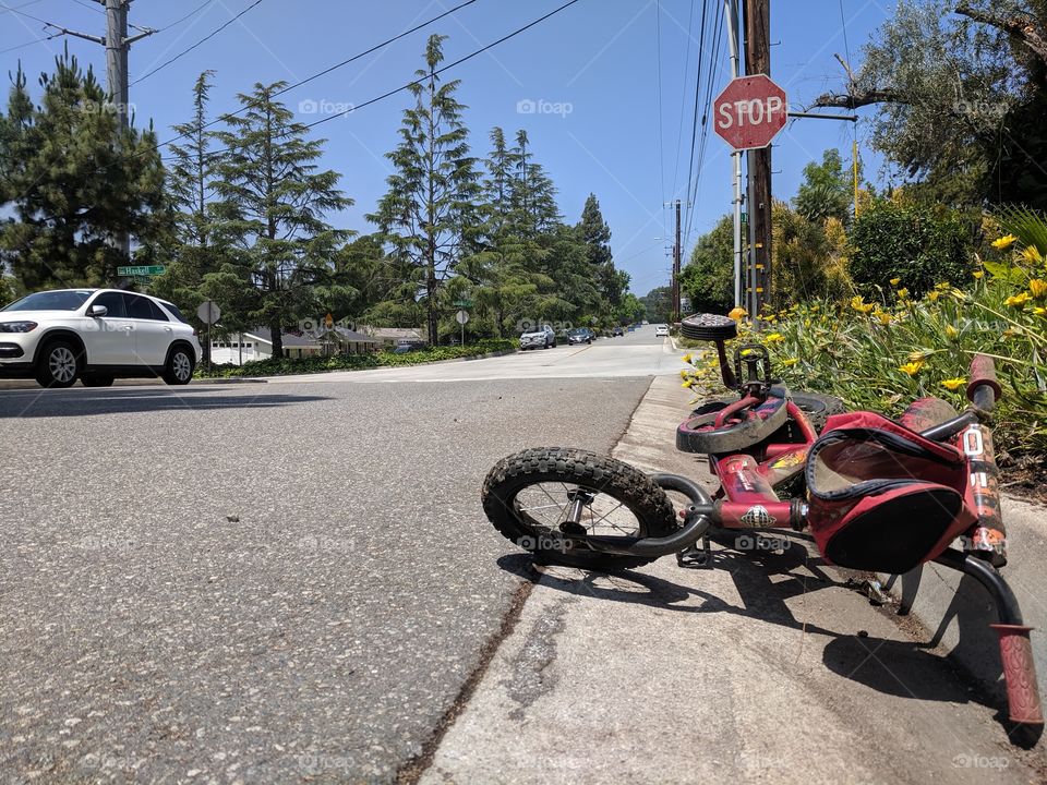 A discarded child's bicycle on the street in front of a stop sign.
