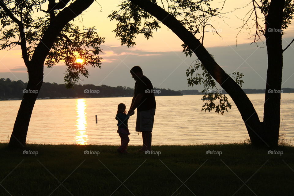 Darling loving silhouetted photo of young girl with her Dad in between two trees! 