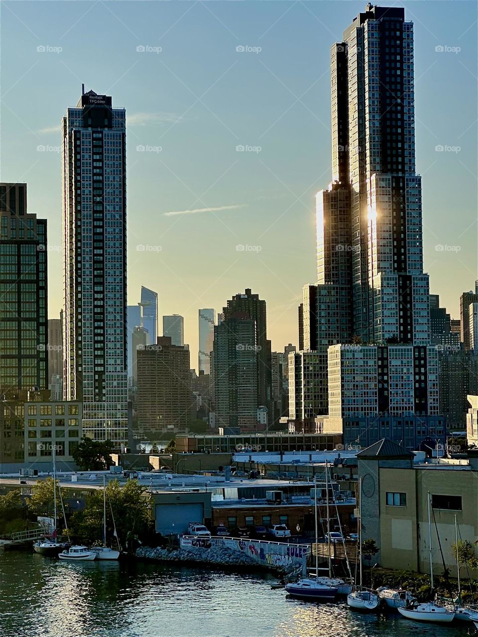 Here is in extreme closeup the LIC shore at “Newtown Creek” with its many boats seen from the “Pulaski Bridge” that connects “Greenpoint”, Brooklyn to LIC, Queens. In the distance we see “Manhattan”. 2024. Hypnotic Productions