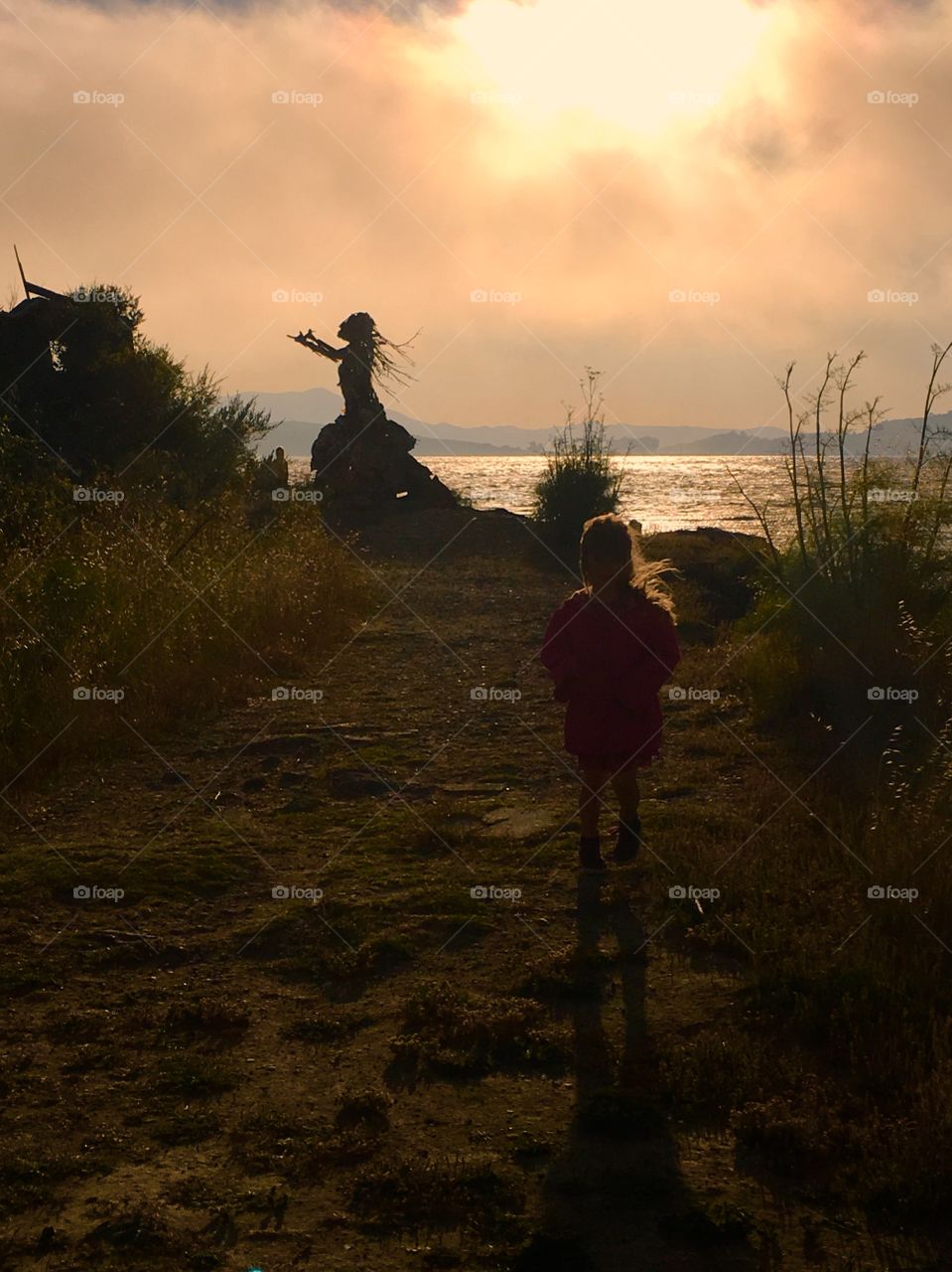 Little girl walking away from statue on Albany Bulb, island. CA.