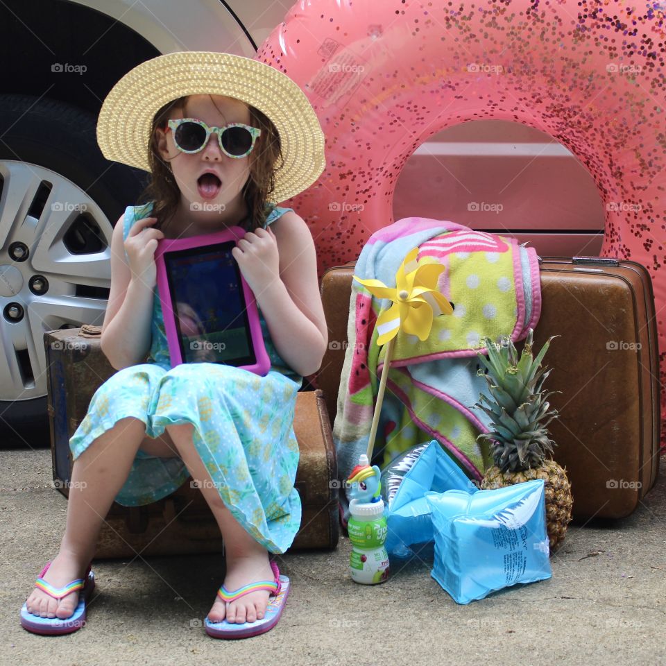 A cute young girl ready to go on a vacation trip becomes bored with waiting and starts having some fun making faces.