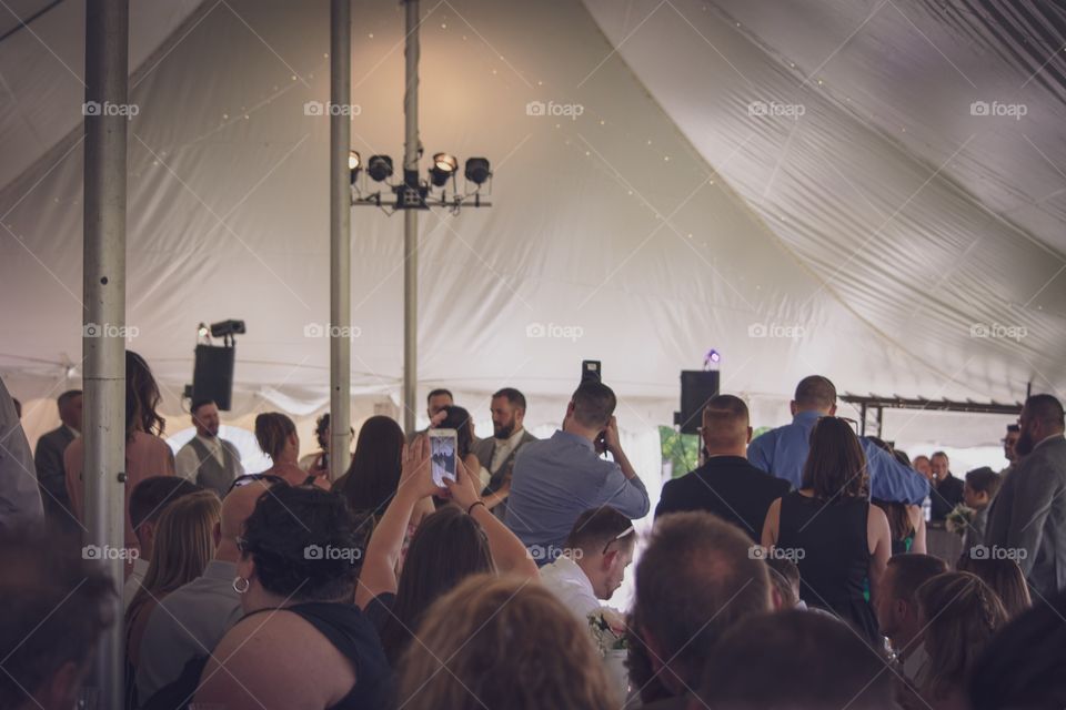 People holding cell (or mobile) phones during the bride and groom’s first dance at their wedding in order to photograph it.