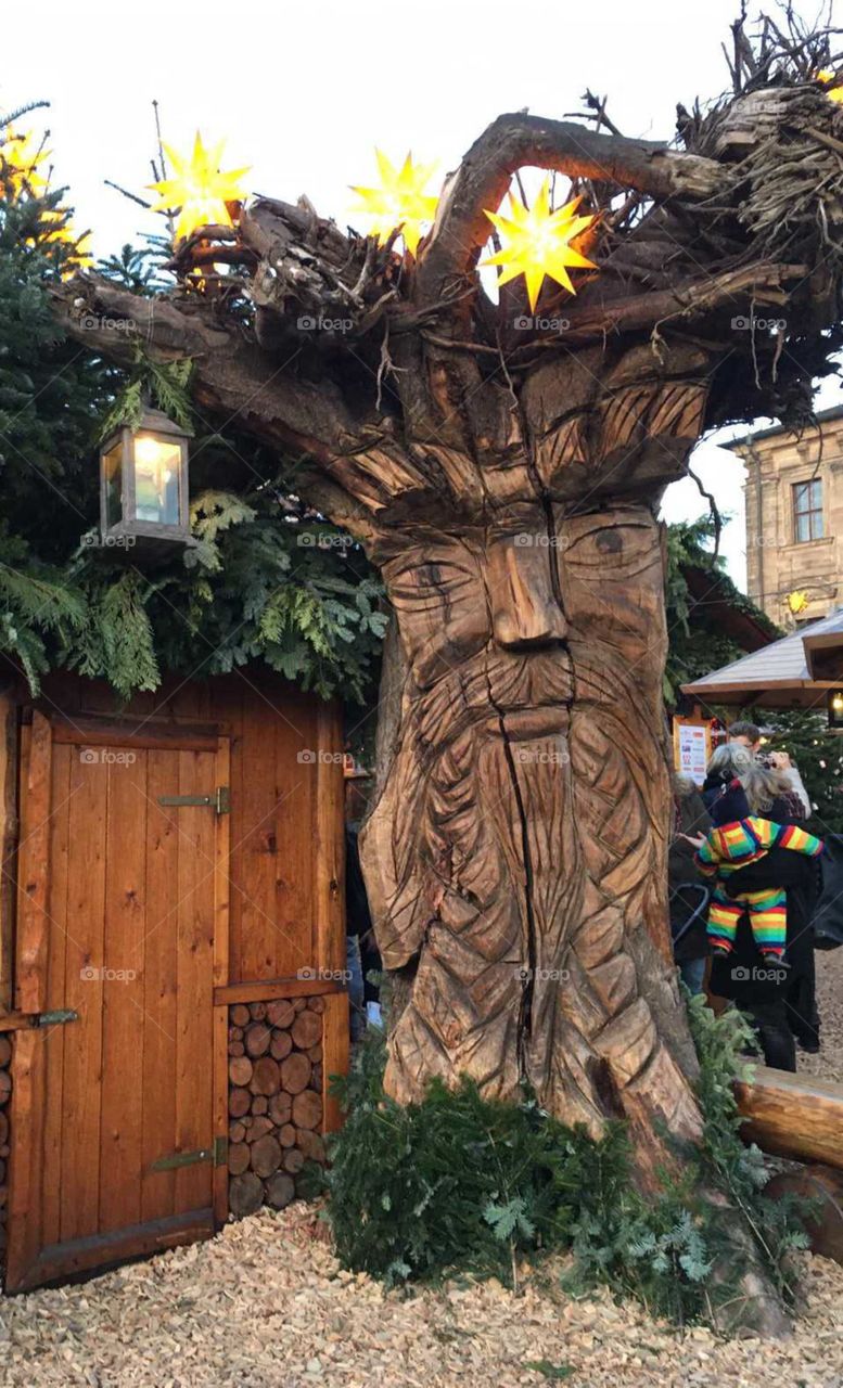 Holzskulptur,freundlicher Baum
steht auf einem Weihnachtsmarkt,
schaut sehr freundlich