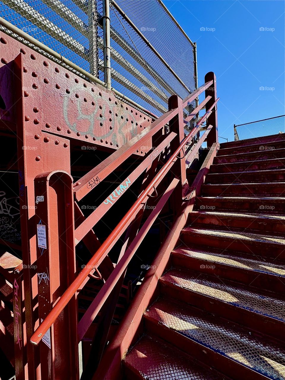 This is the red metal staircase of the “Pulaski Bridge” at “Newtown Creek” that connects LIC, Queens to “Greenpoint”, Bklyn. Its style reminds in many ways of the “Bauhaus” design school in “Weimar”, Germany of the 1930s. 2024. Hypnotic Productions