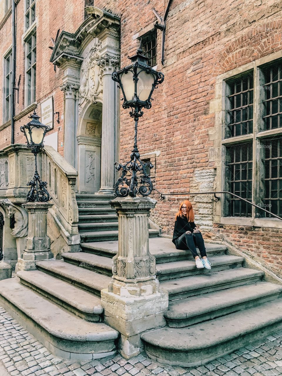 Young girl sitting on staircase of building