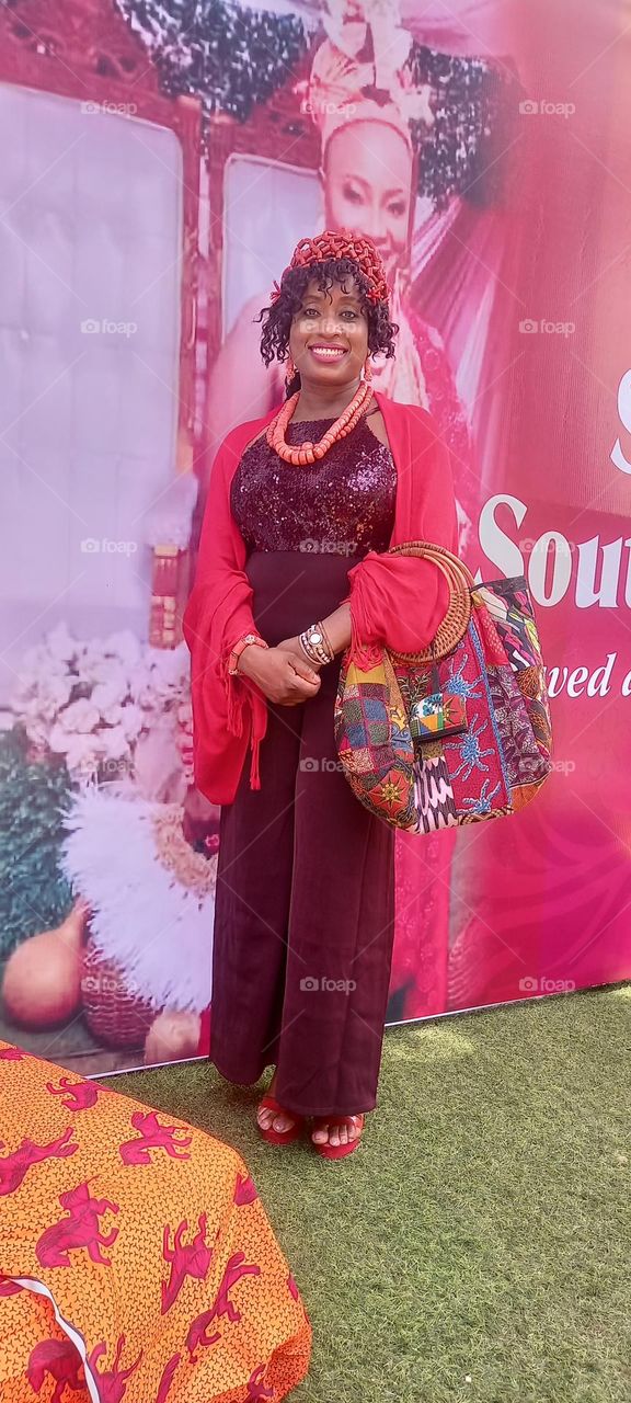 Traditional Edo native in Edo coral beads and a dressy burgundy urban  jump suit