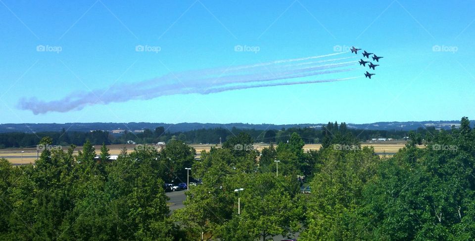 Blue Angel jets flying over trees and buildings during an Air show in Oregon on a clear day