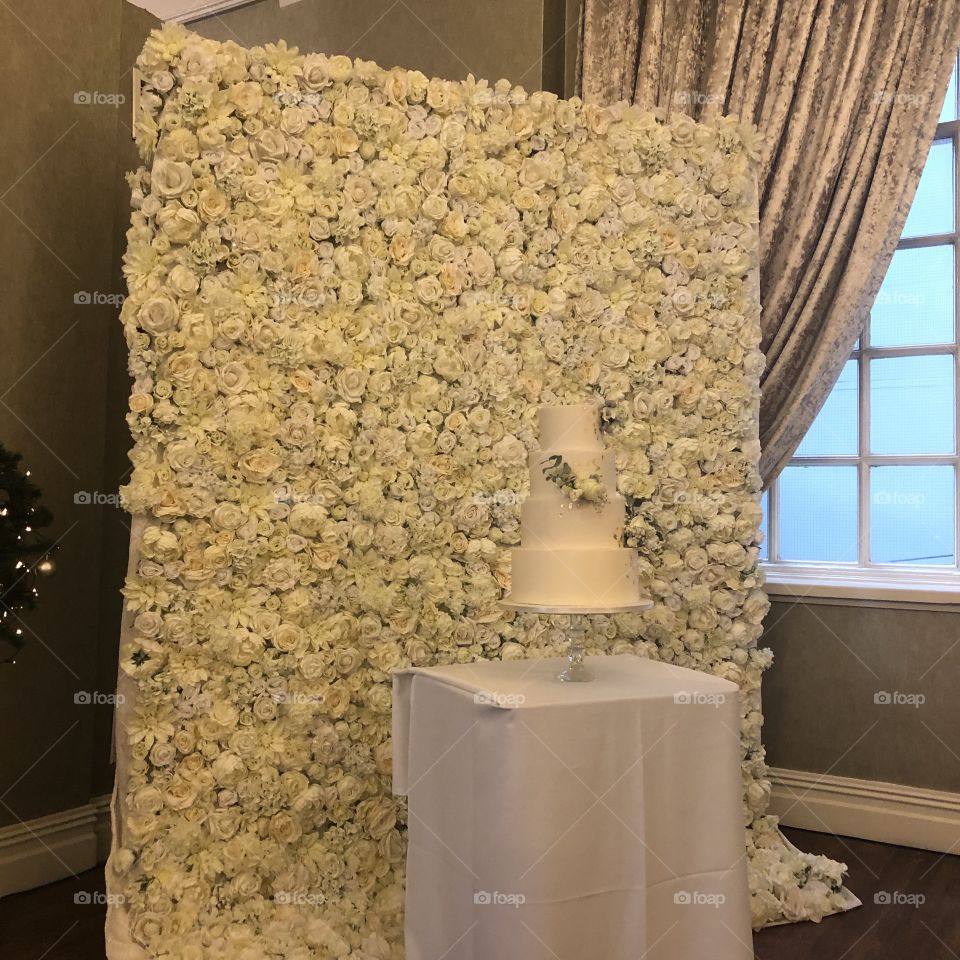 Wedding cake against flower wall 
