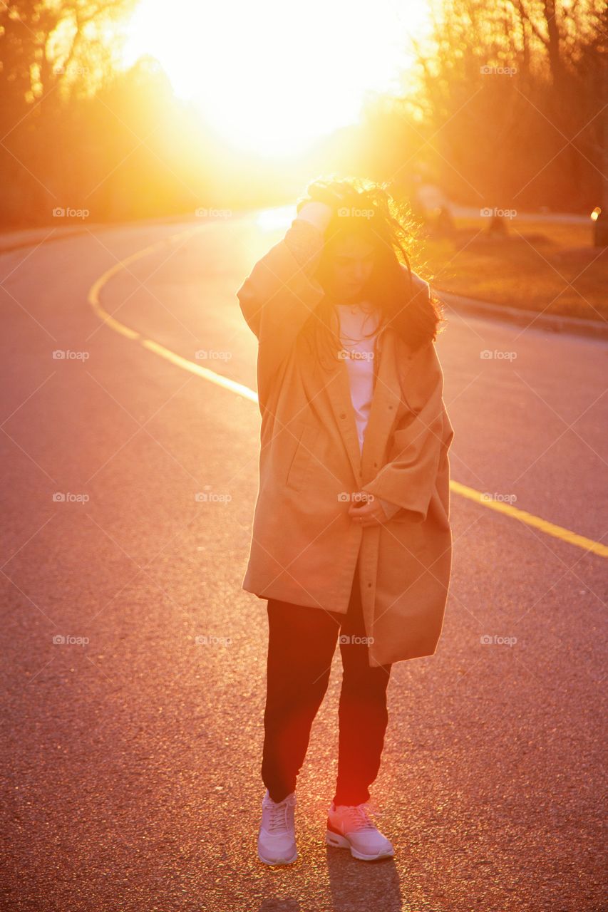 A young woman caught in gorgeous rays of a bright sunset