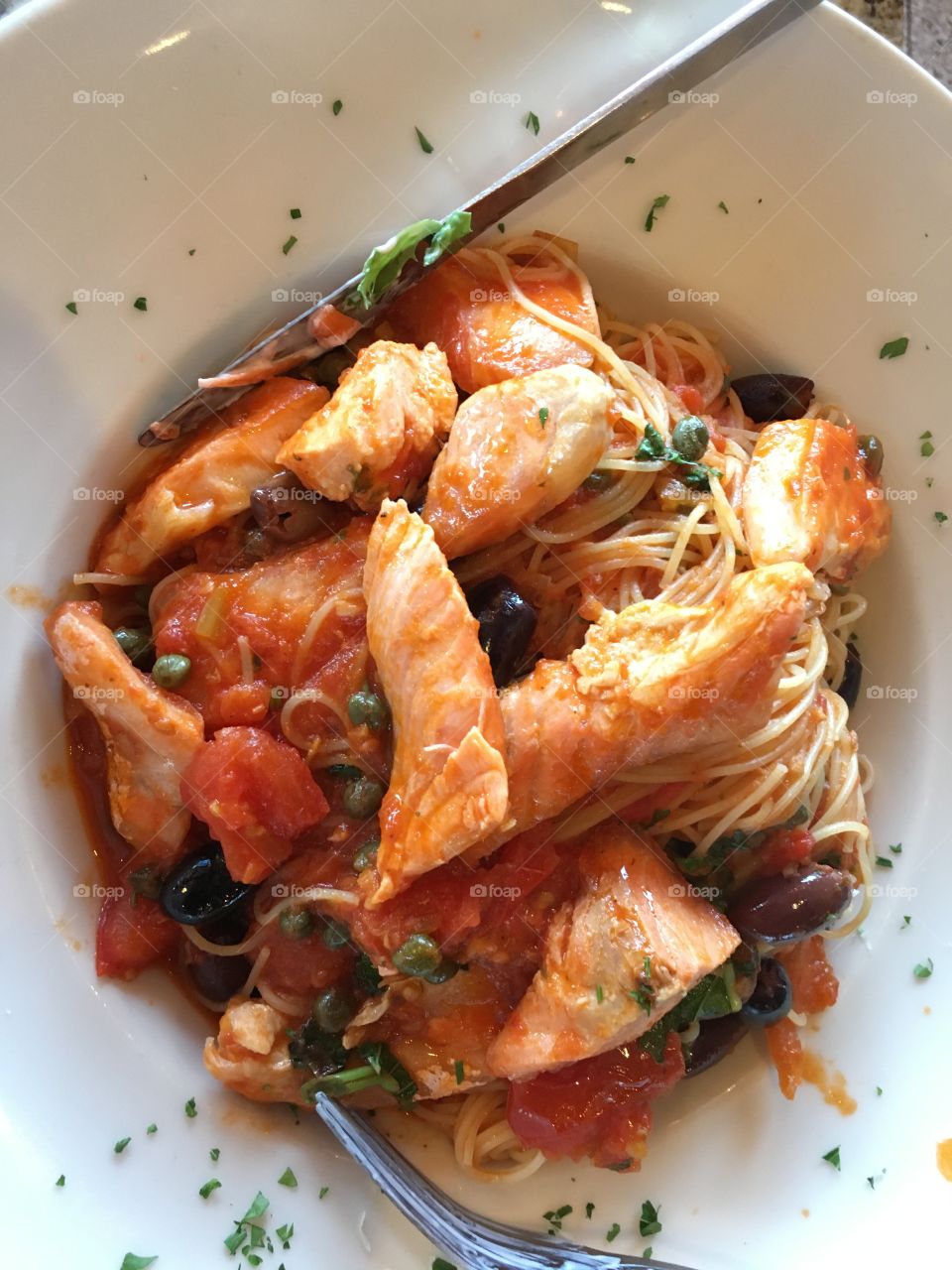 Salmon medallions with capers over pasta