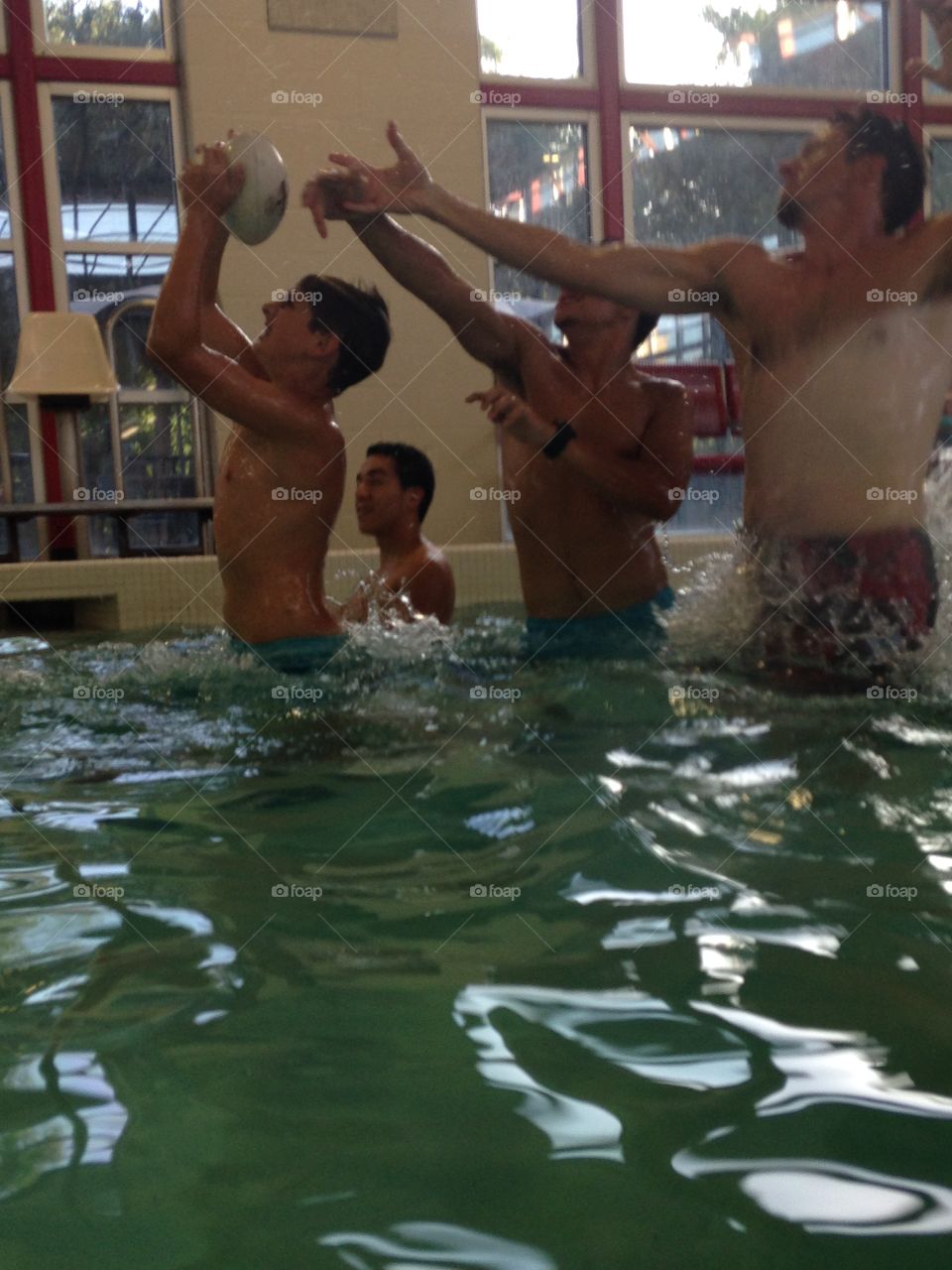 Water sports. Boys jumping out of the water to catch a football