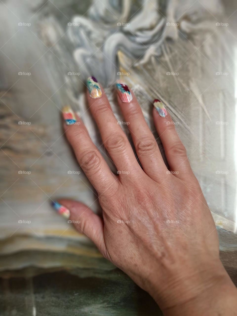Mano con uñas pintadas multicolor