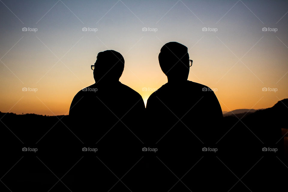 Brothers looking at the horizon with a lovely sunset as background