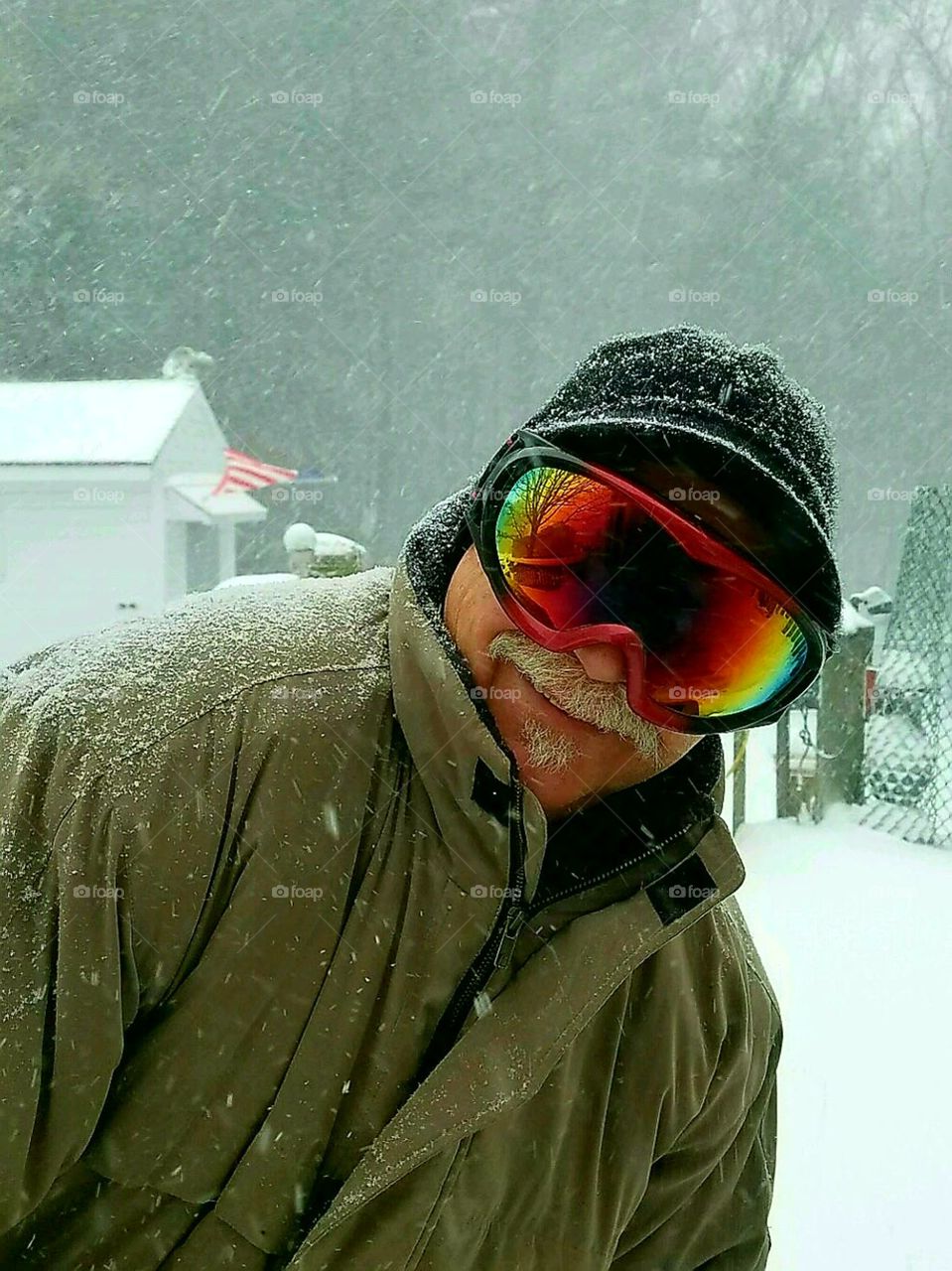Out in the snowstorm dressed for cold & ice while clearing snow away.  Ski goggles on.