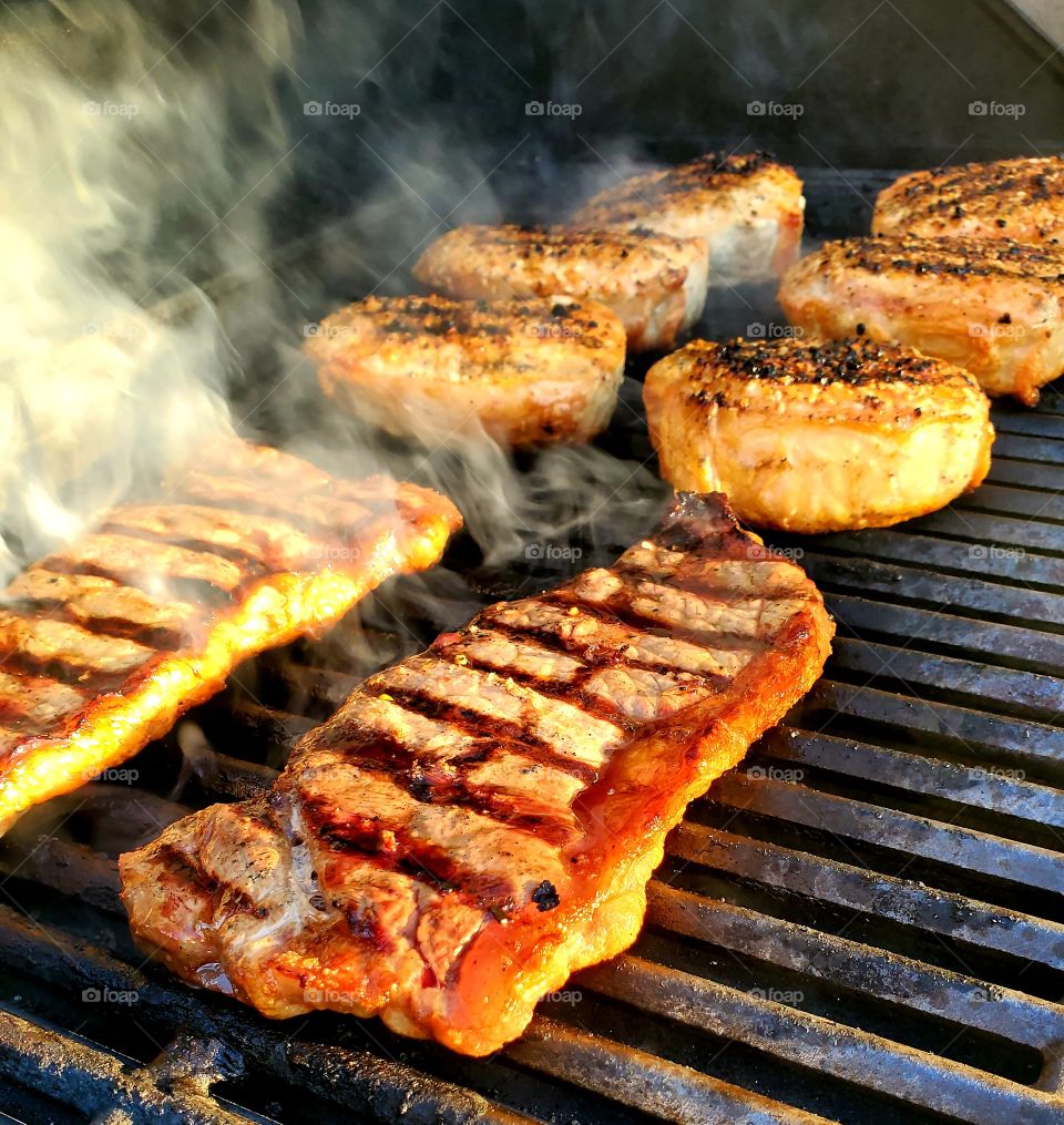 Steaks and pork chops share a grill