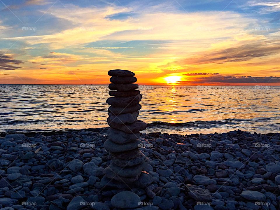 Beautiful sunset on the beach with pile of stones