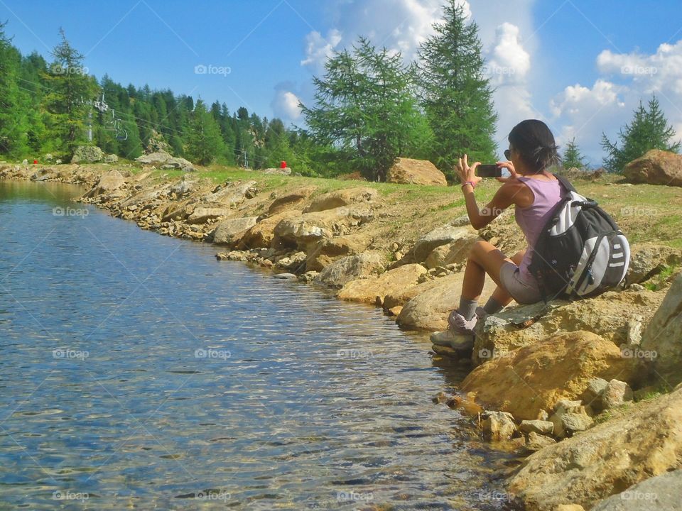 Woman is Taking a Photo beside a mountain lake