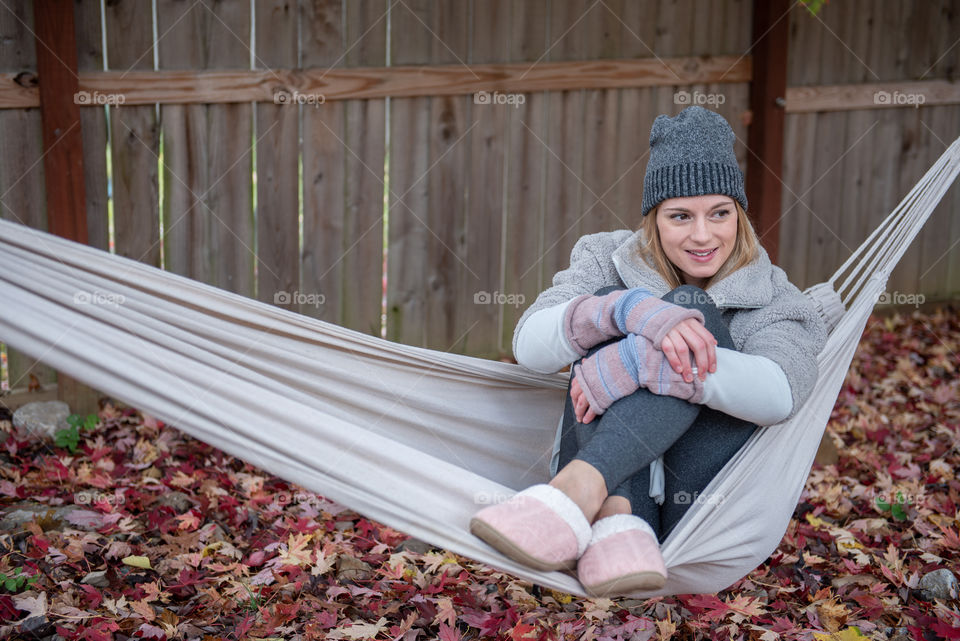 Young millennial woman smiling and sitting in a hammock outdoors in the fall