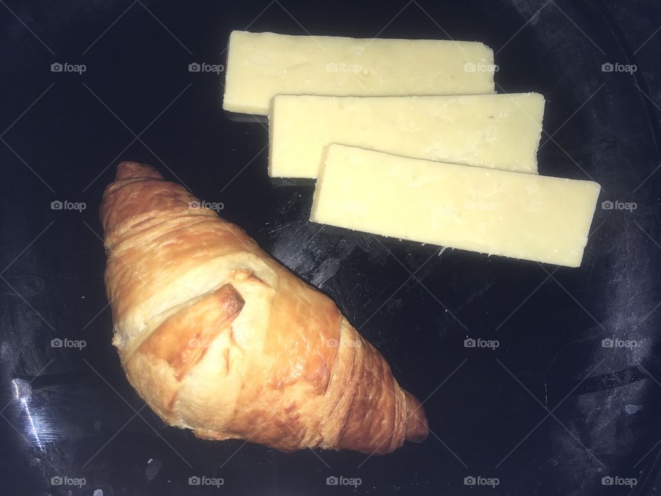 Croissant and cheese on black plate for breakfast 
