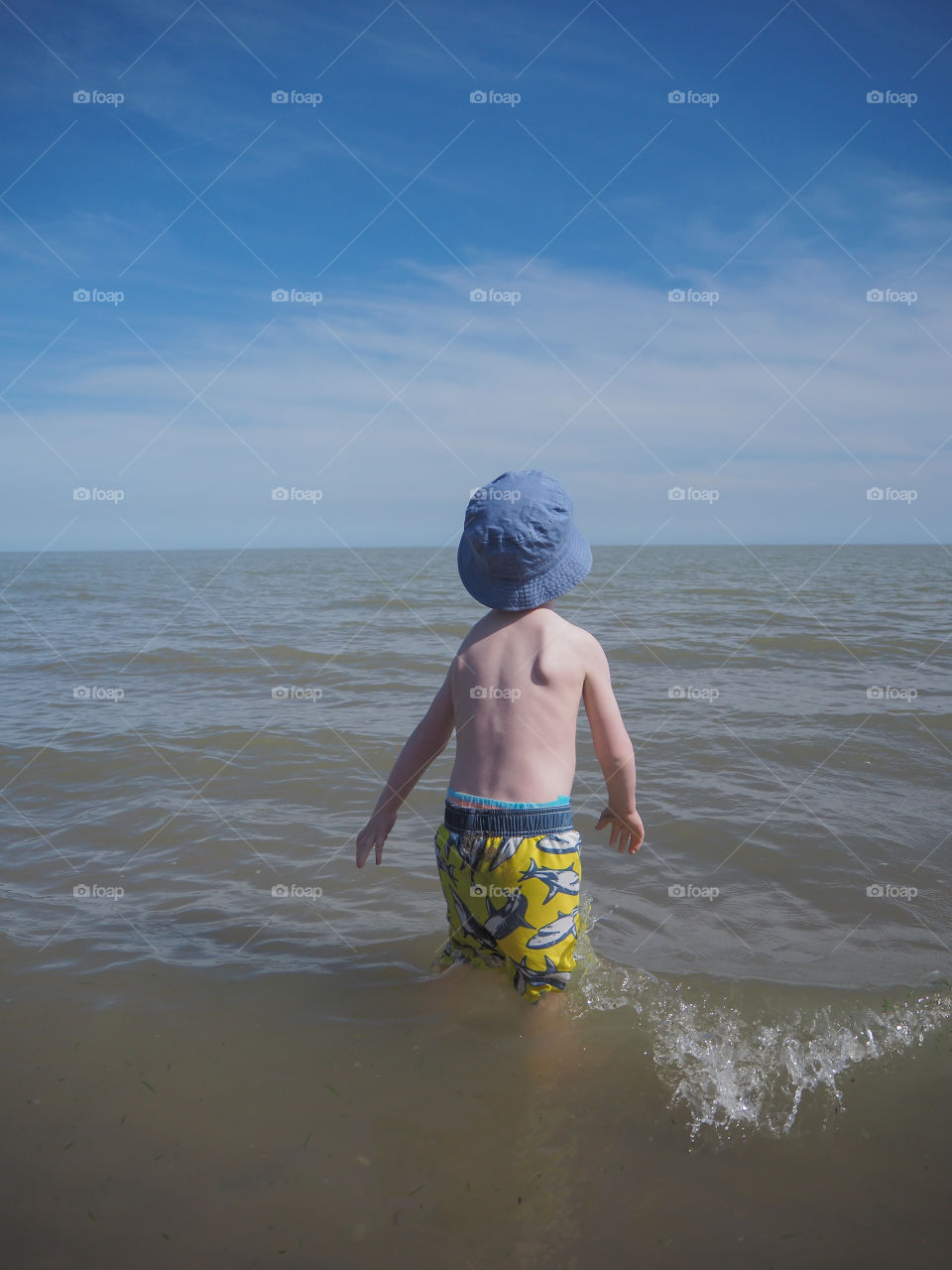 Toddler boy playing in the ocean water.