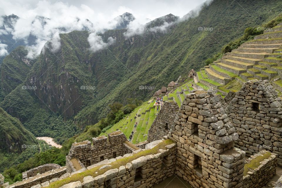 Machu Picchu farming terraces. View towards farming terraces at Machu Picchu. Few ruins in the front. Steep forest covered mountains in the background 