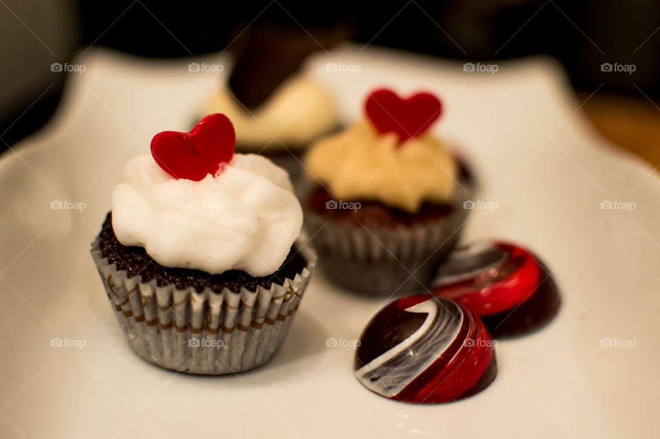 Chocolate cupcakes with red candy hearts and dark chocolate truffles with red and white swirl decoration artisanal chocolate gourmet photography 