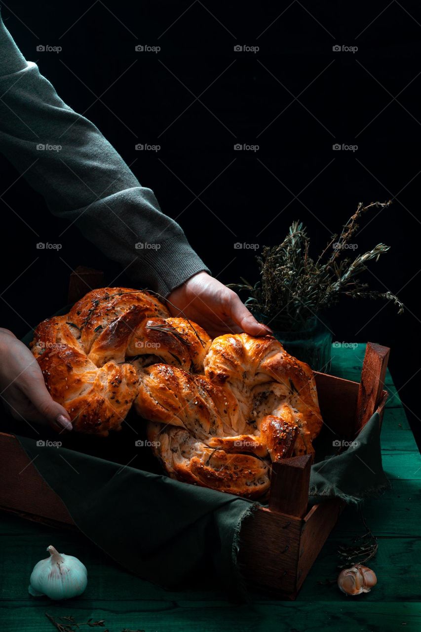 Rosemary twisted loaf bread on a green wooden background, still life, rustic style.