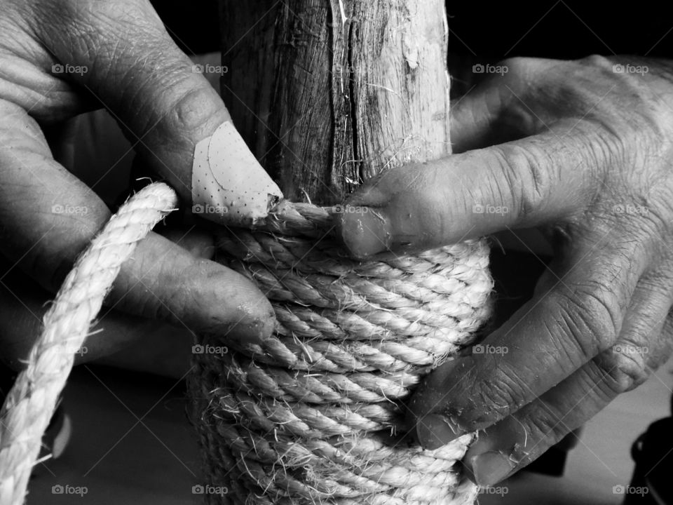 Human hand with rope and wooden pole