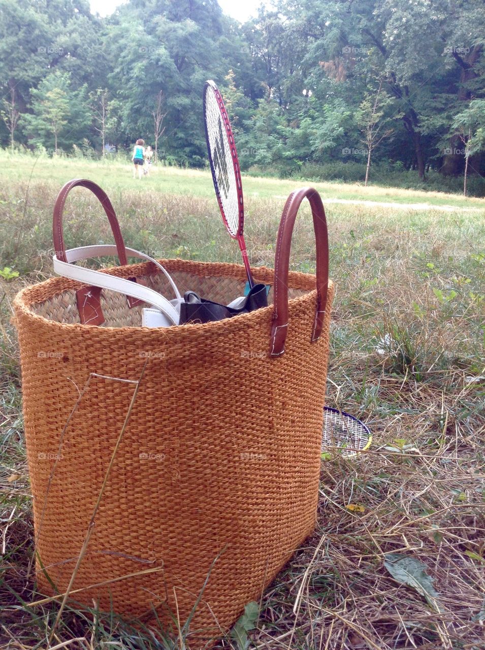 A basket with badminton on the grass in park in picnic