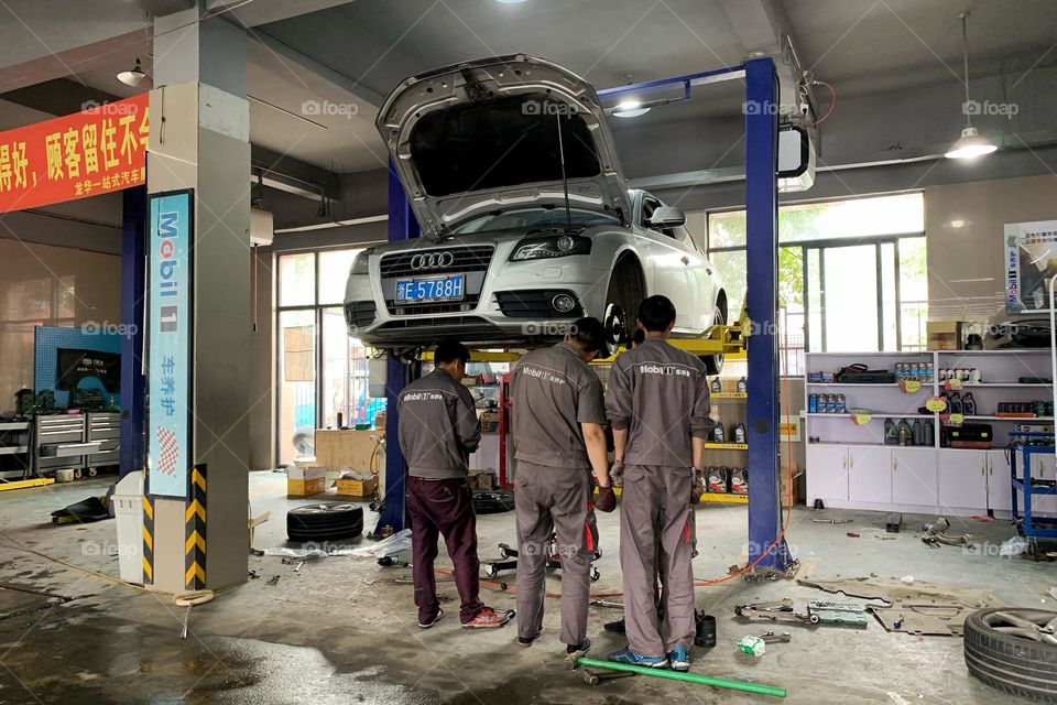 Group of mechanics discussing about repairing a car 