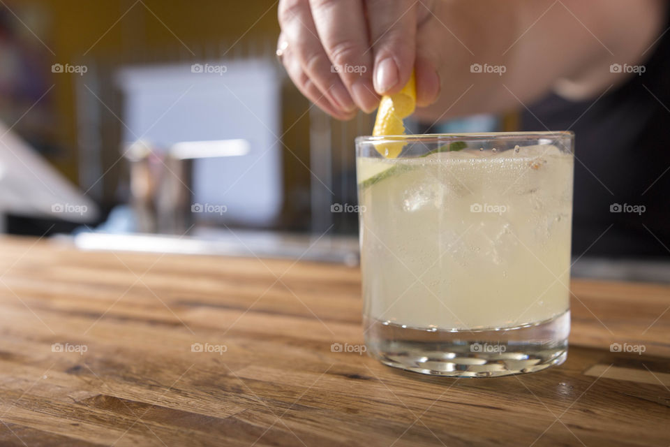 Person hand holding lime with cocktail glass on table