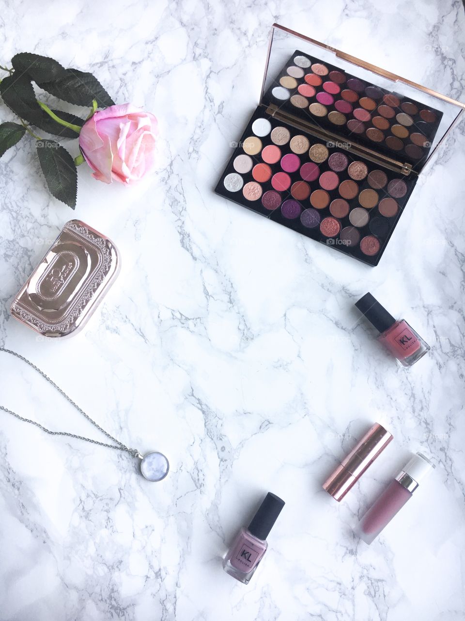 Makeup flat lay on a marble background, pink, eyeshadow palette, nail polish and makeup brushes.