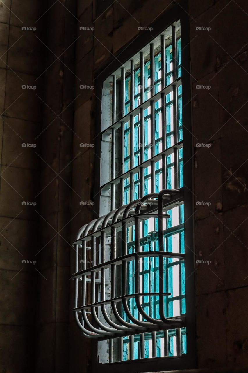Windows with bars on them in a corner of Alcatraz federal prison in San Francisco California with the light illuminated inside the dark damp prison