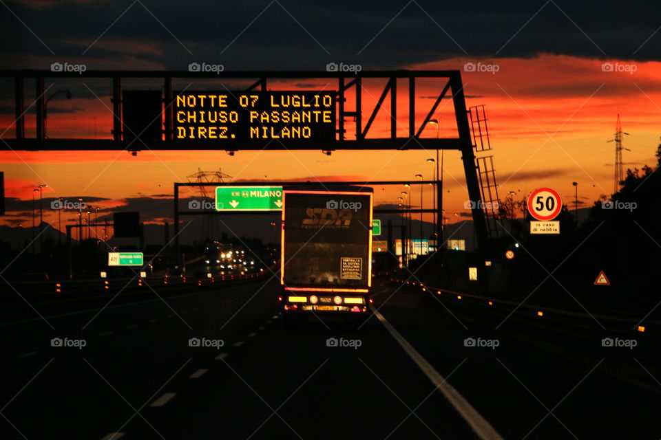 A beautiful orange sunset sky and motorway skyline with lights and lighting truck
