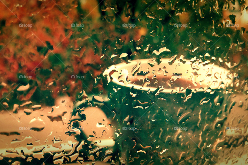Autumn mood, a coffee cup behind of the window glass, raindrops on the window