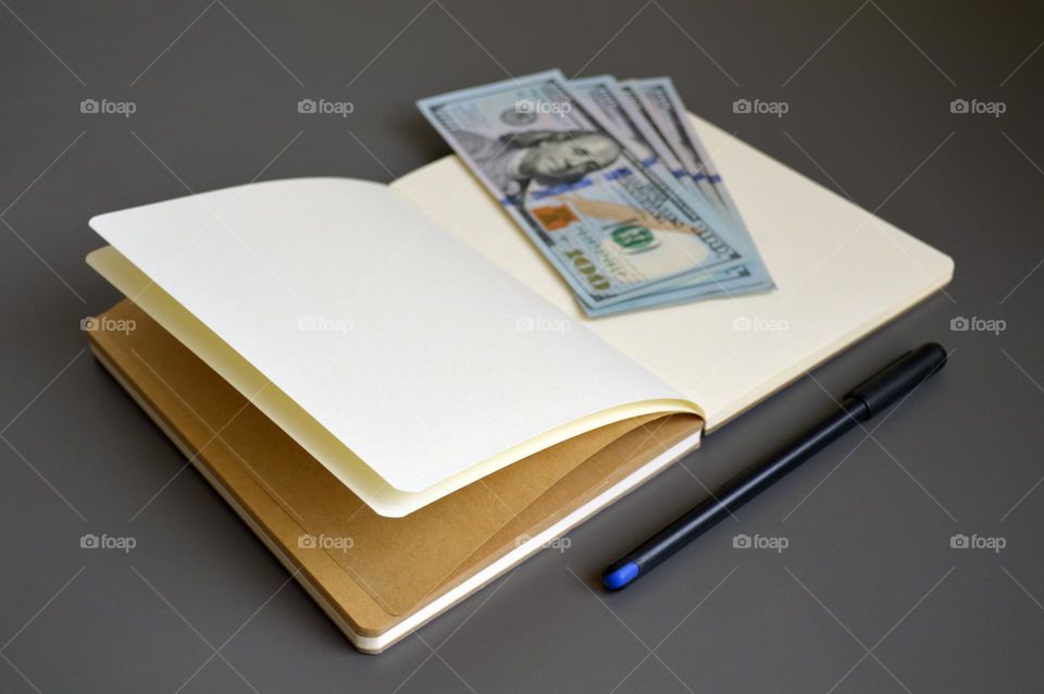 Dollars on the table with a notebook