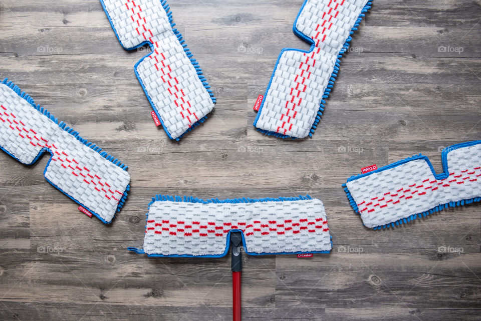 Flat lay of an O-Cedar mop and microfiber mop head refills on a hardwood floor